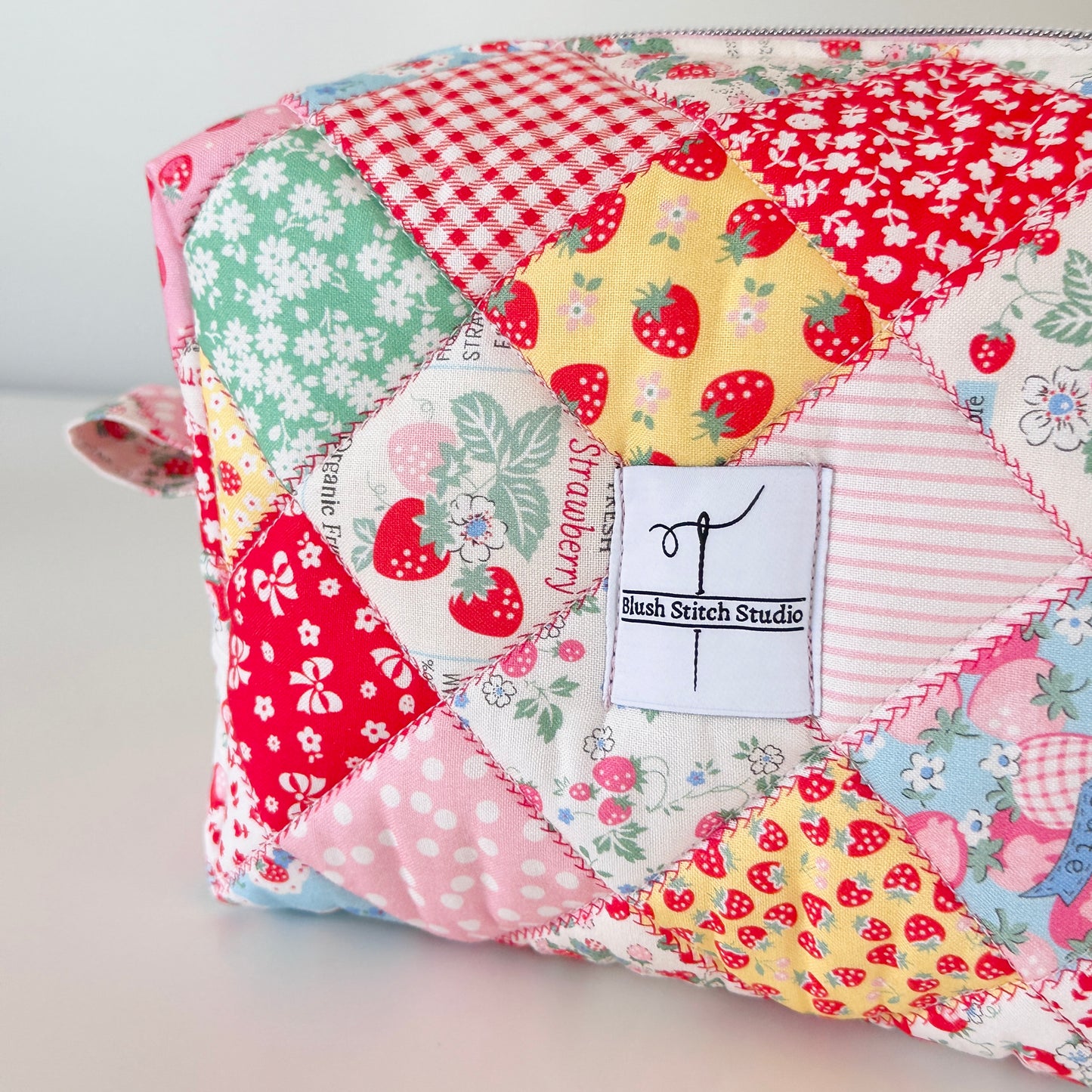 Patchwork pouch with colorful patterns and 'Bush Stitch Studio' label on a light background