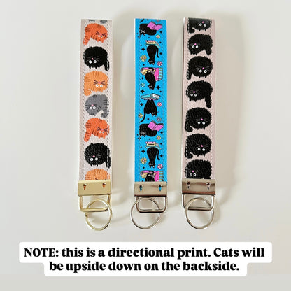 Three keychains with cat-themed designs on a white background