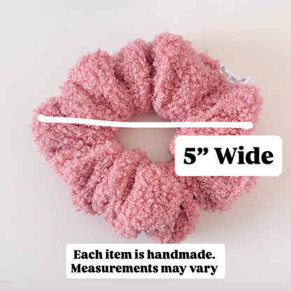 Pink textured scrunchie with a white measuring tape and text indicating width and handcrafted nature.