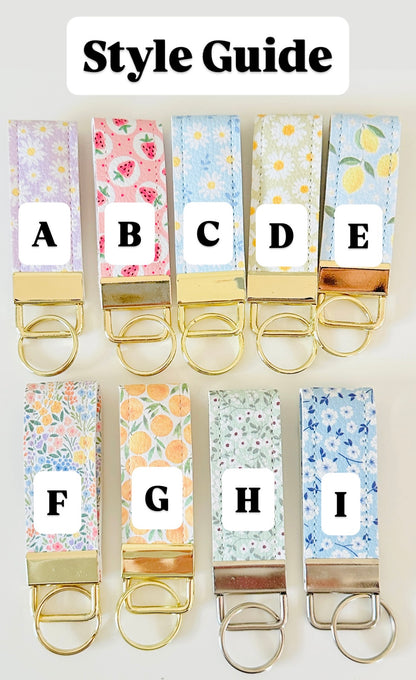 Set of colorful keychains with floral patterns and letter labels on a white background.