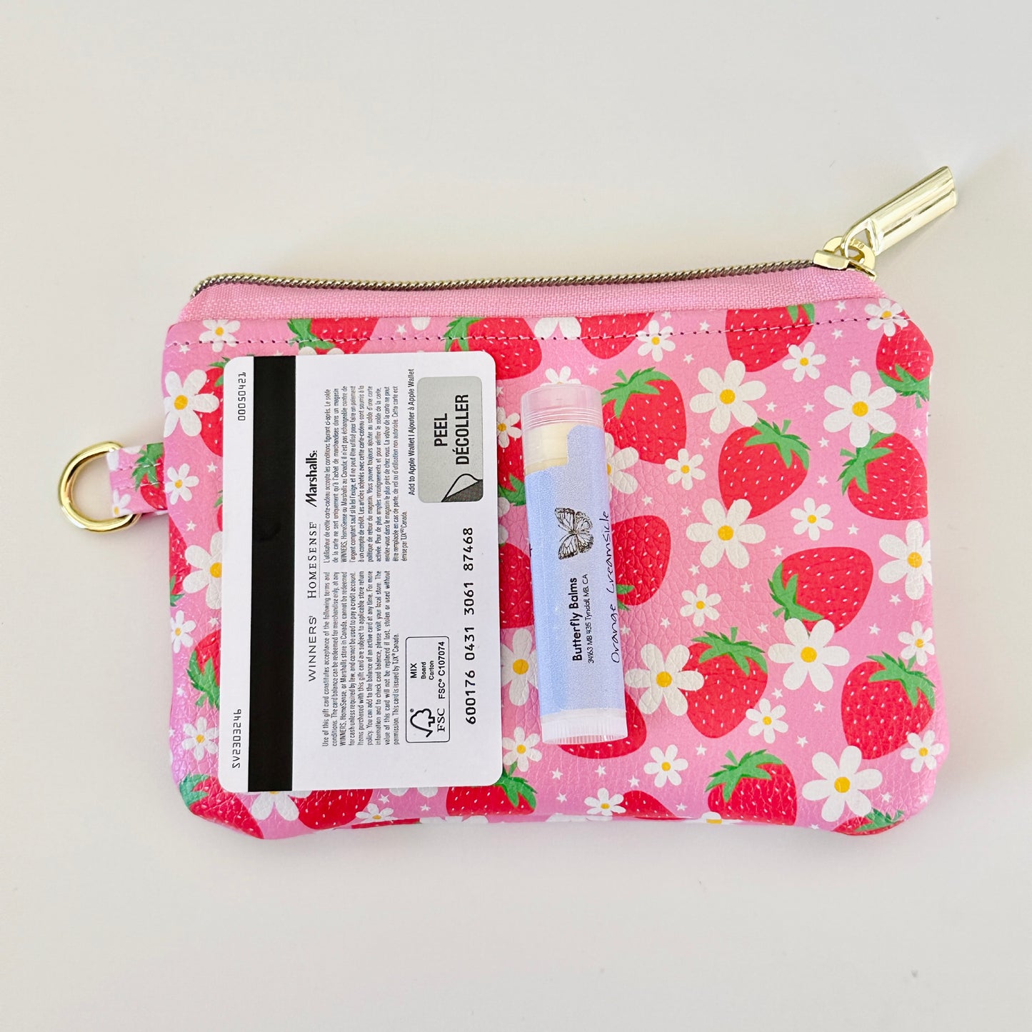 Pink strawberry coin purse with a daisy pattern on a white background