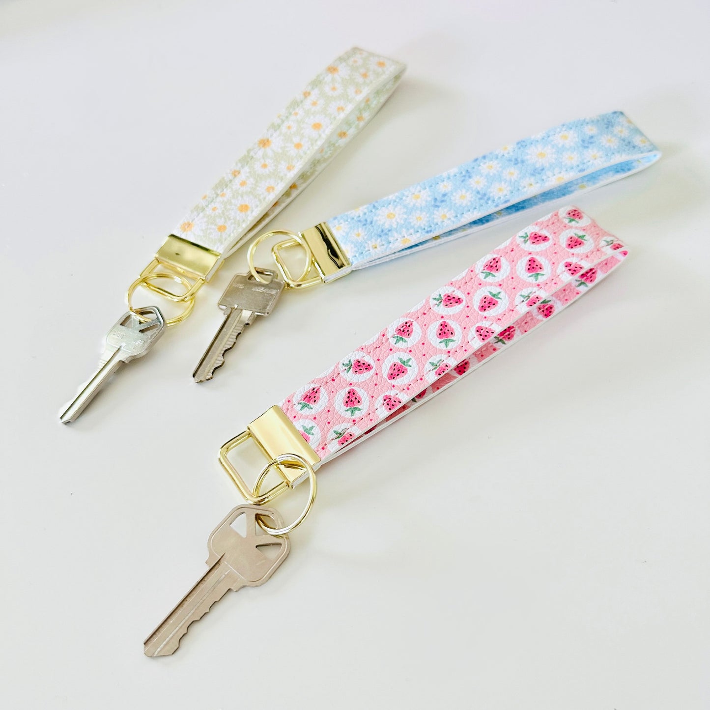 Three keys with floral keychains on a light background