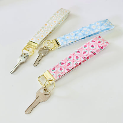 Three keys with floral keychains on a light background