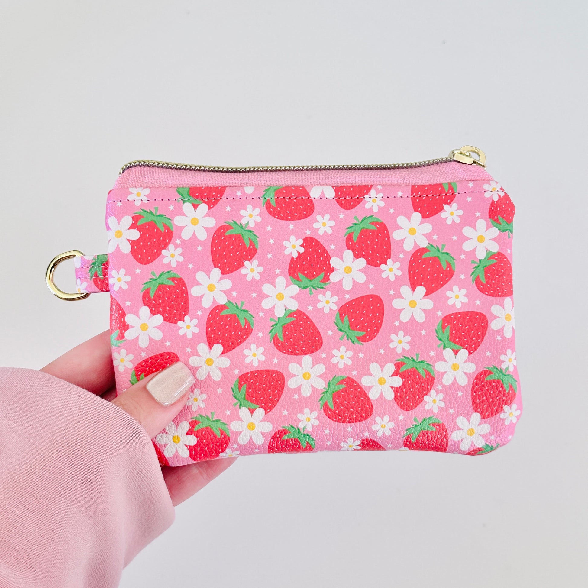 Pink strawberry coin purse with a daisy pattern on a white background