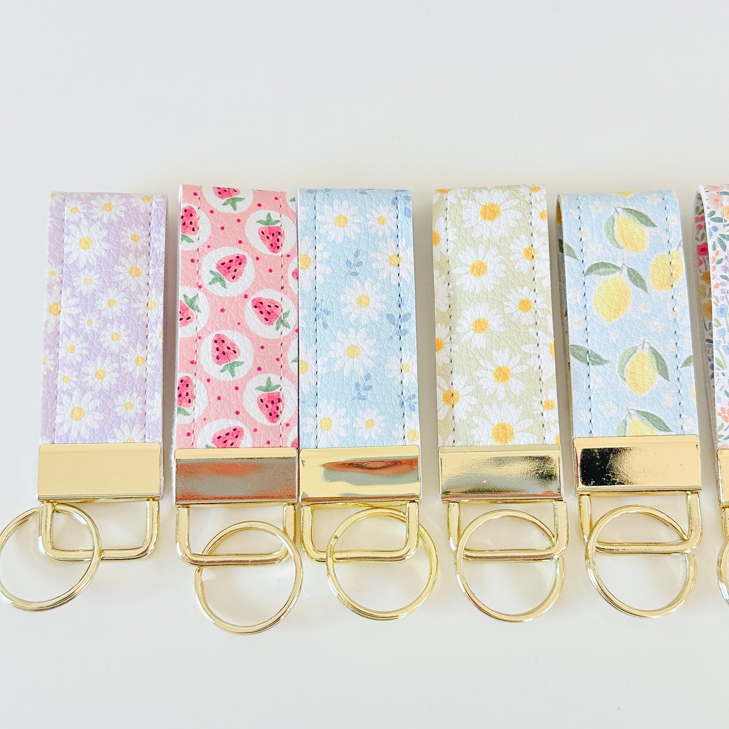daisy floral and strawberry keychains with gold hardware made from vegan leather 