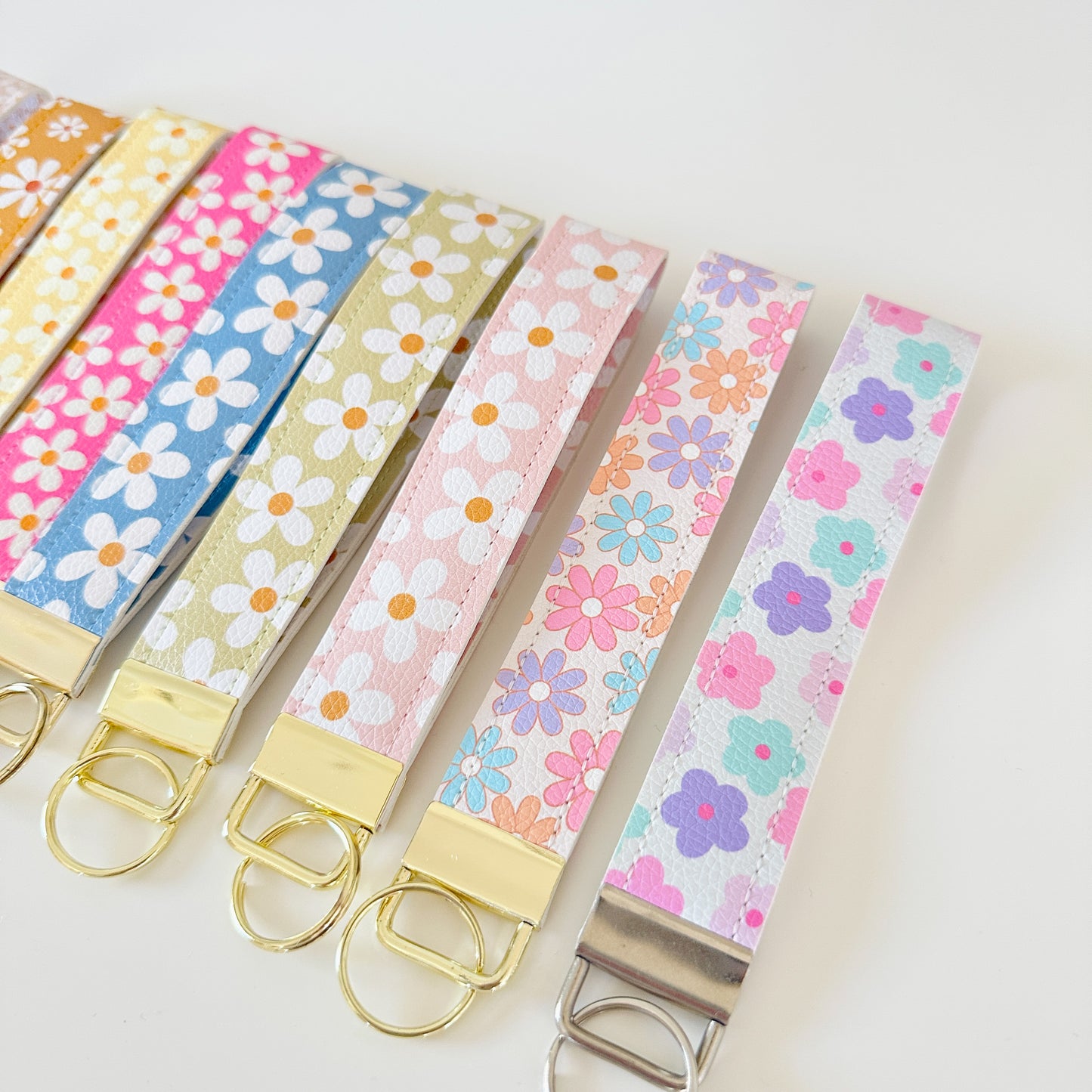 Set of colorful floral keychains with gold and silver keyrings on a white background