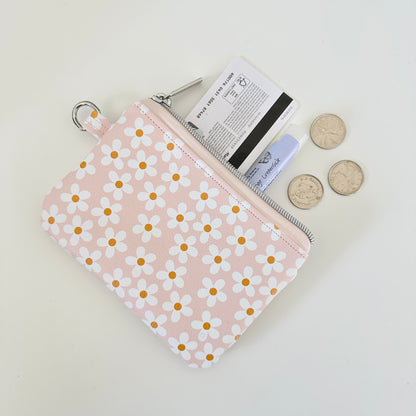 Floral-patterned coin purse with coins and cards on a light background