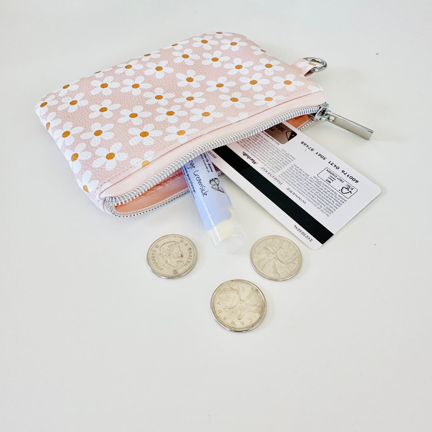 Floral-patterned coin purse with coins and cards on a light background