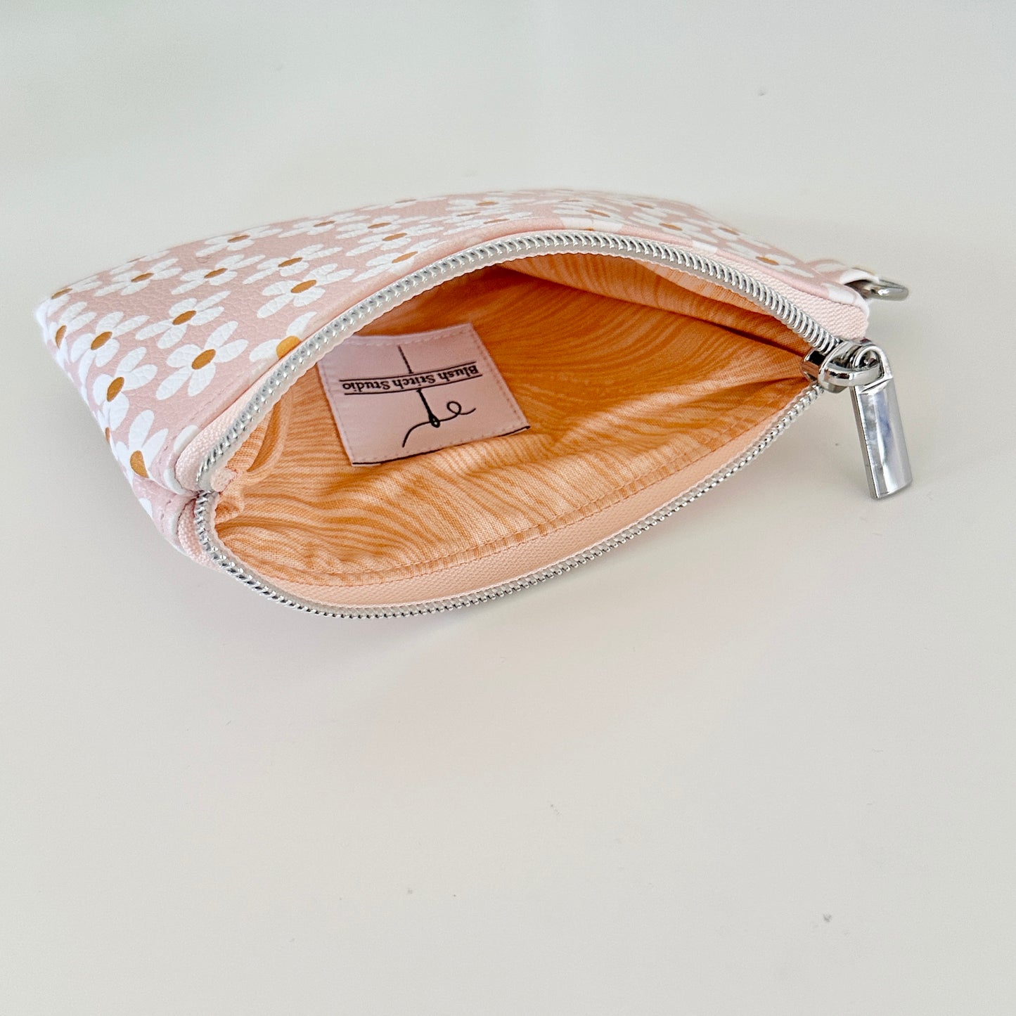 Floral-patterned coin purse with coins and cards on a light background