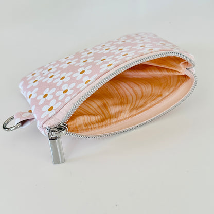 Floral-patterned coin purse with coins and cards on a light background