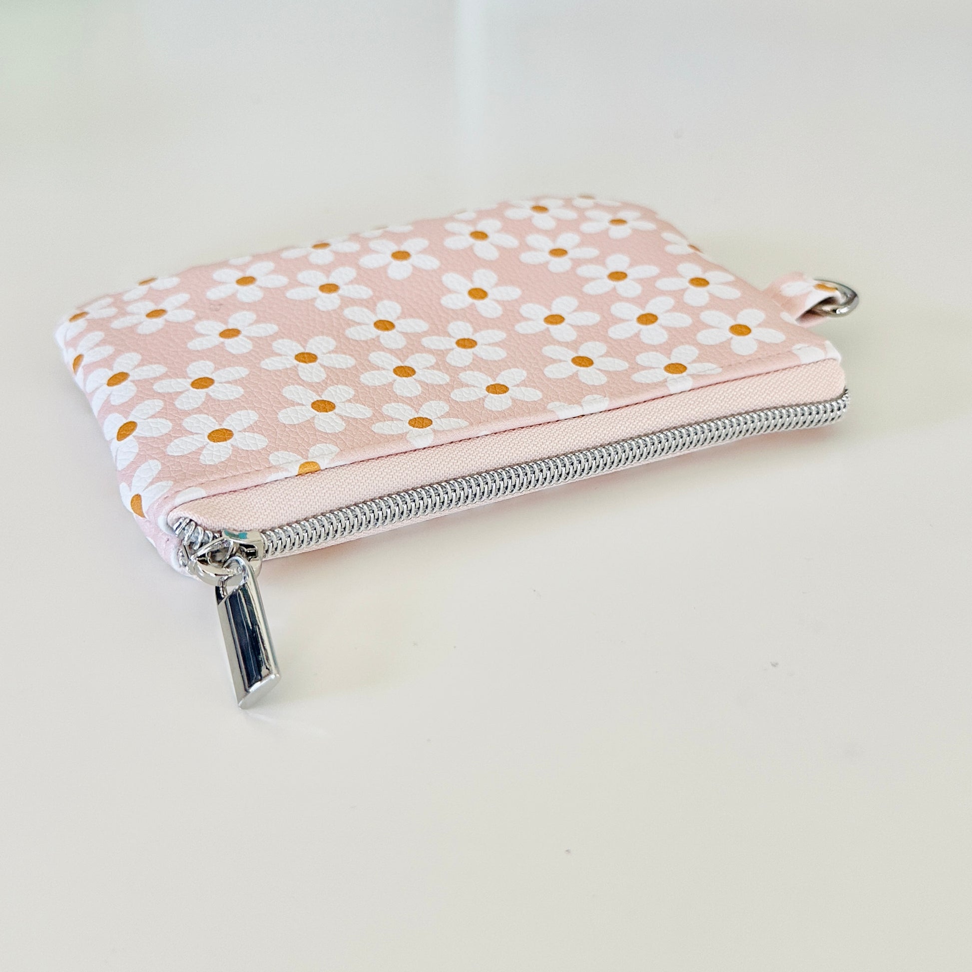 Floral-patterned coin purse with coins and cards on a light background