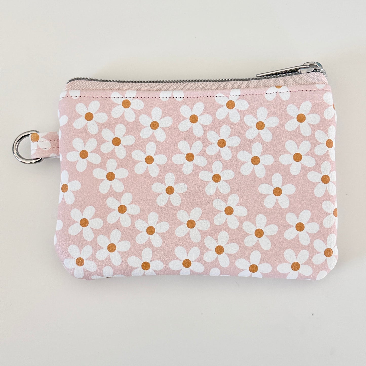 Floral-patterned coin purse with coins and cards on a light background