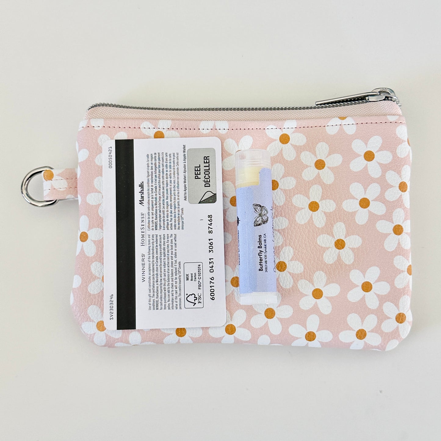 Floral-patterned coin purse with coins and cards on a light background