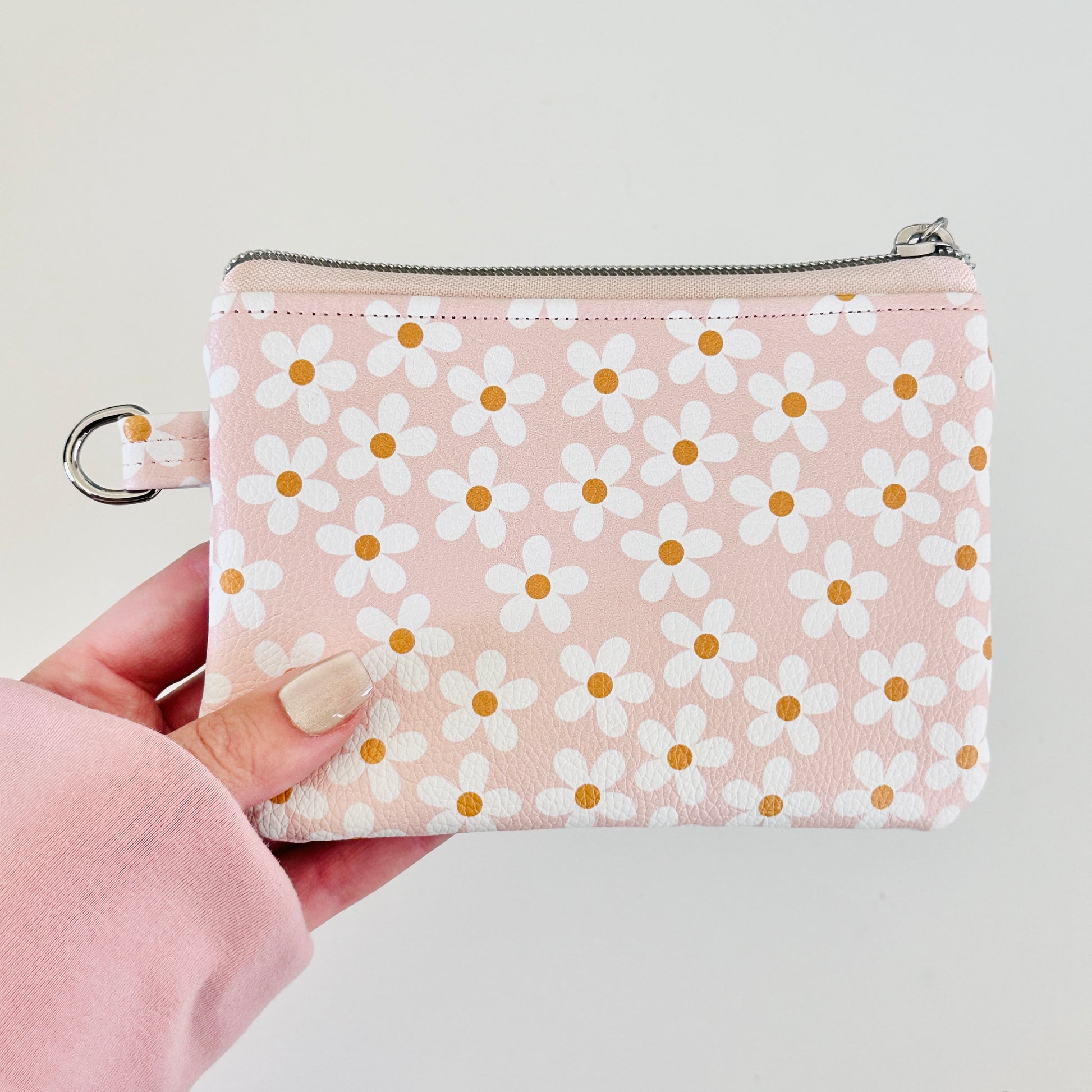 Floral-patterned coin purse with coins and cards on a light background