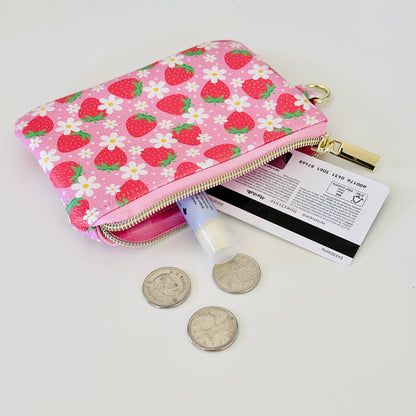 Pink strawberry coin purse with a daisy pattern on a white background