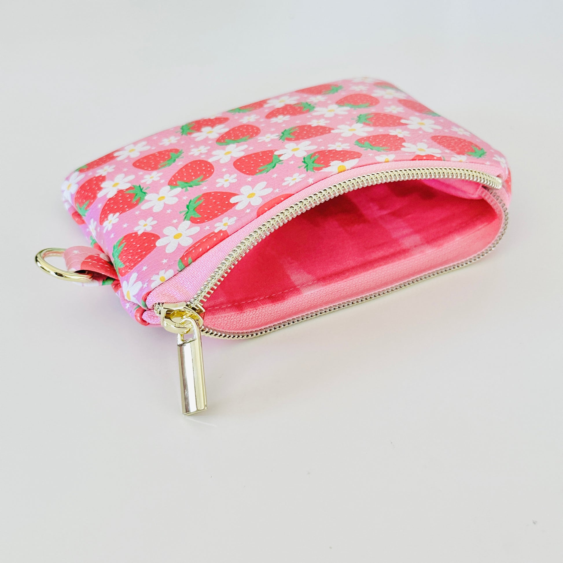 Pink strawberry coin purse with a daisy pattern on a white background