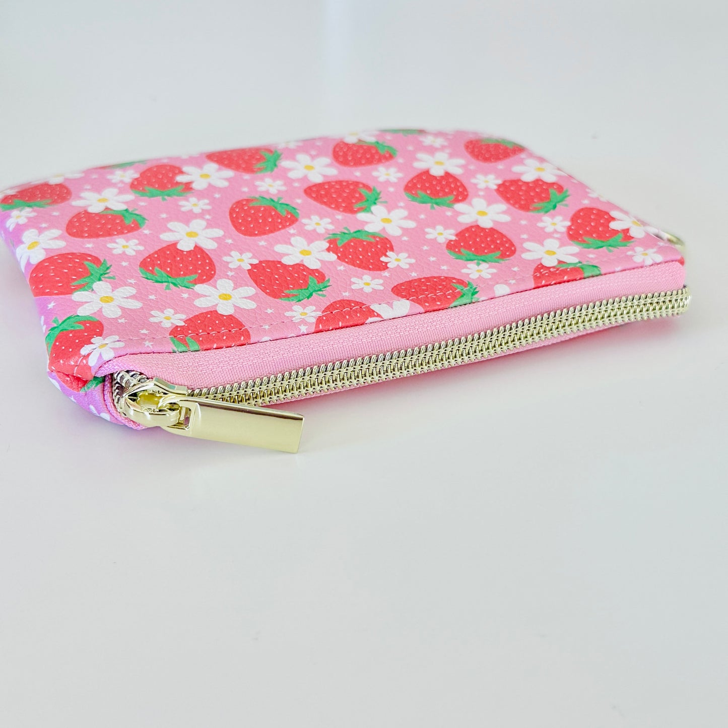 Pink strawberry coin purse with a daisy pattern on a white background