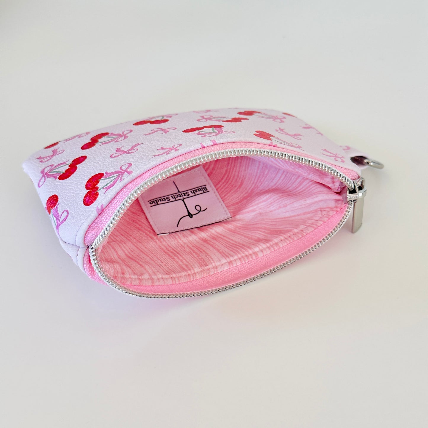 vegan leather coin purse with cherry bow pattern on a white background