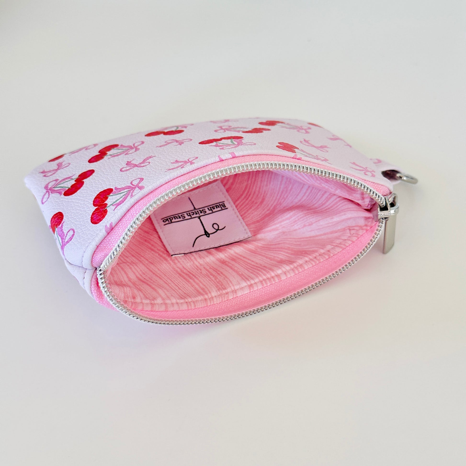 vegan leather coin purse with cherry bow pattern on a white background