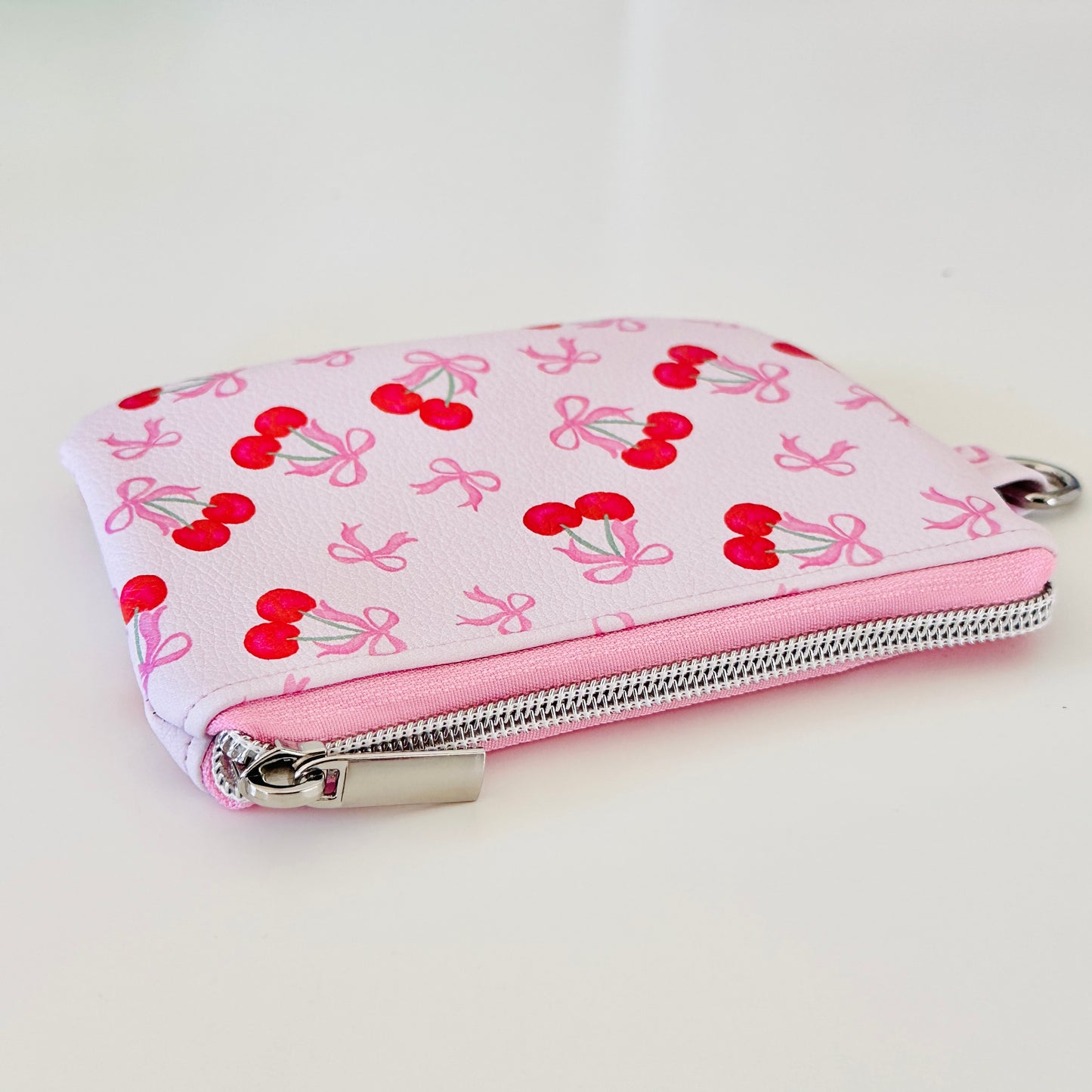 vegan leather coin purse with cherry bow pattern on a white background