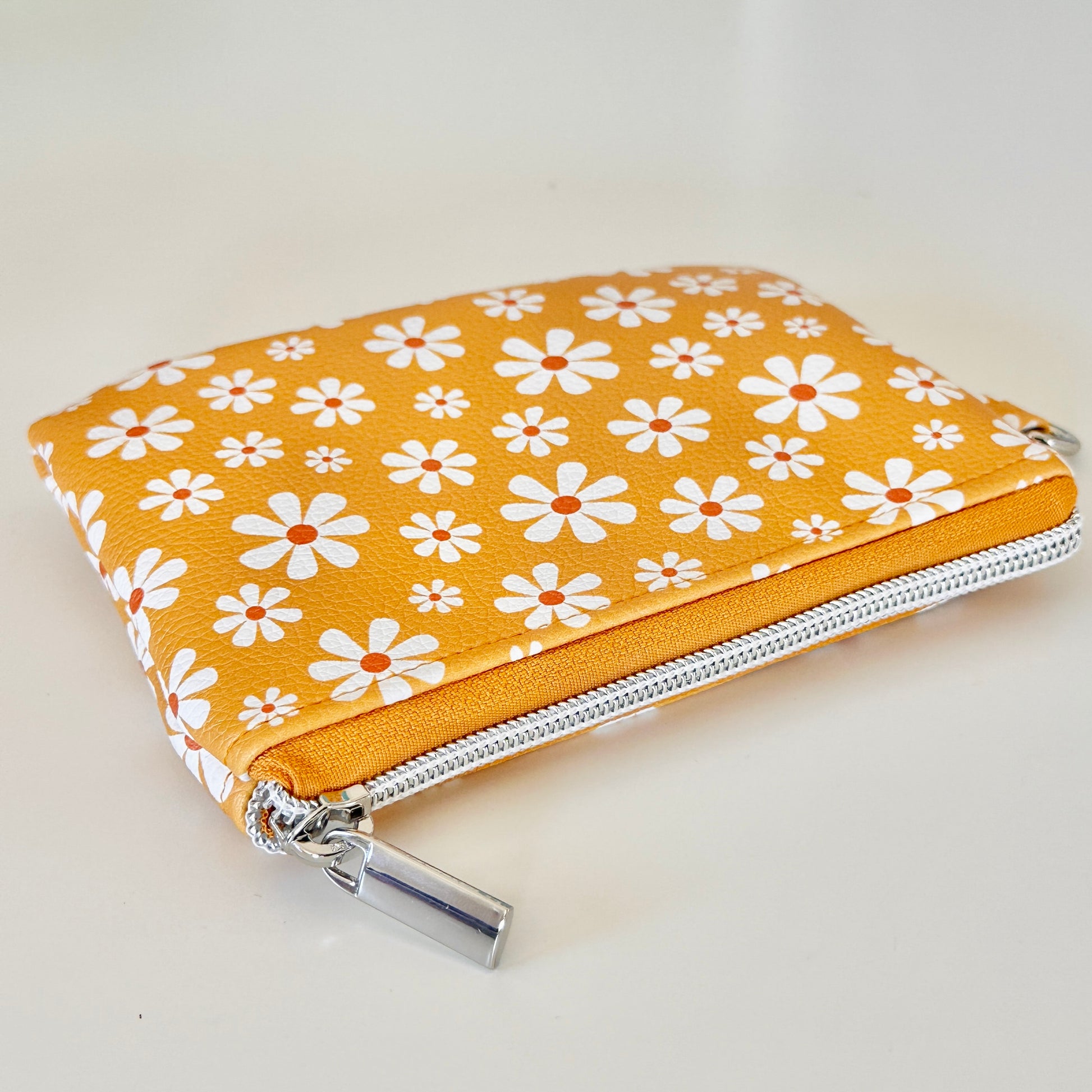 mustard Yellow coin purse with white floral pattern on a white background