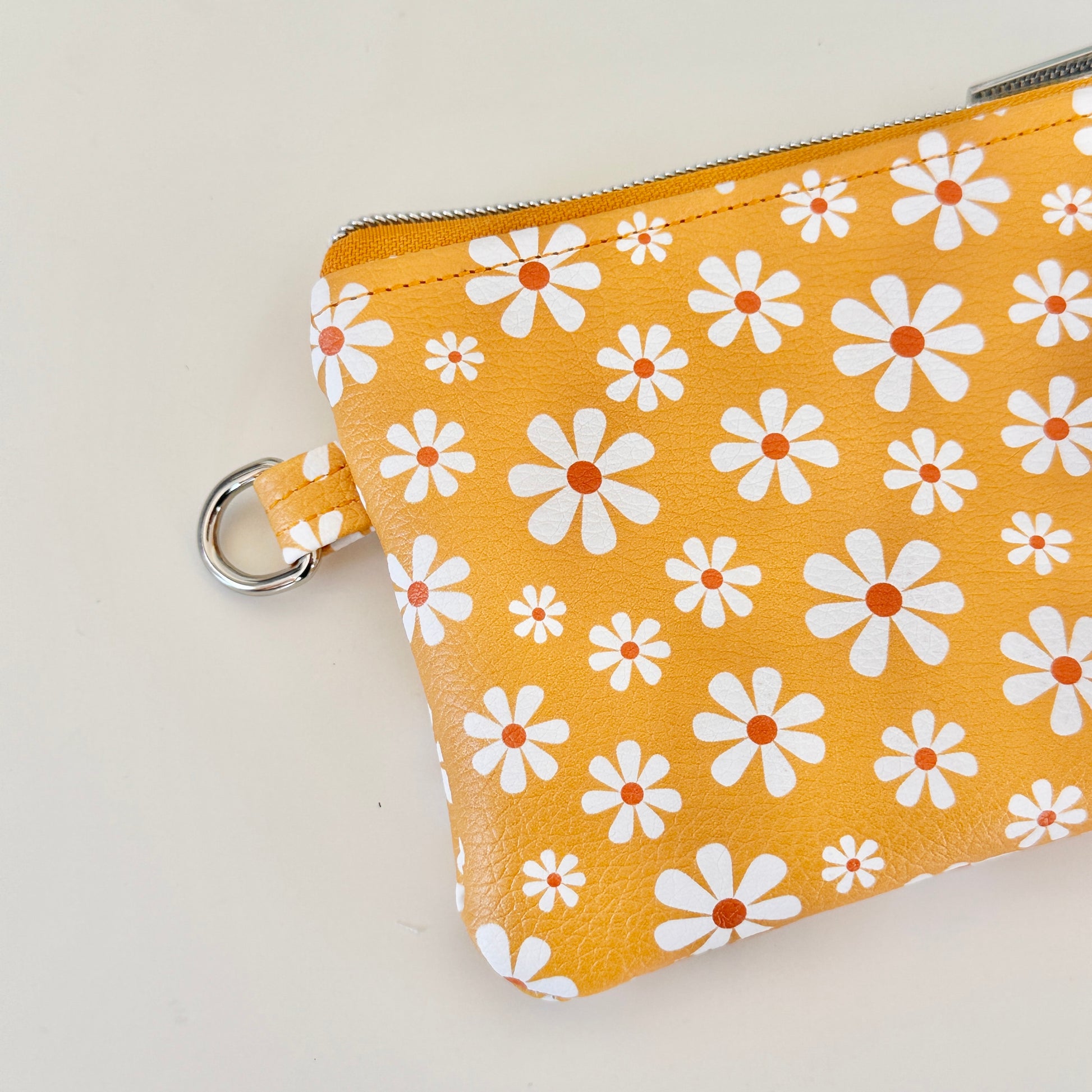 mustard Yellow coin purse with white floral pattern on a white background