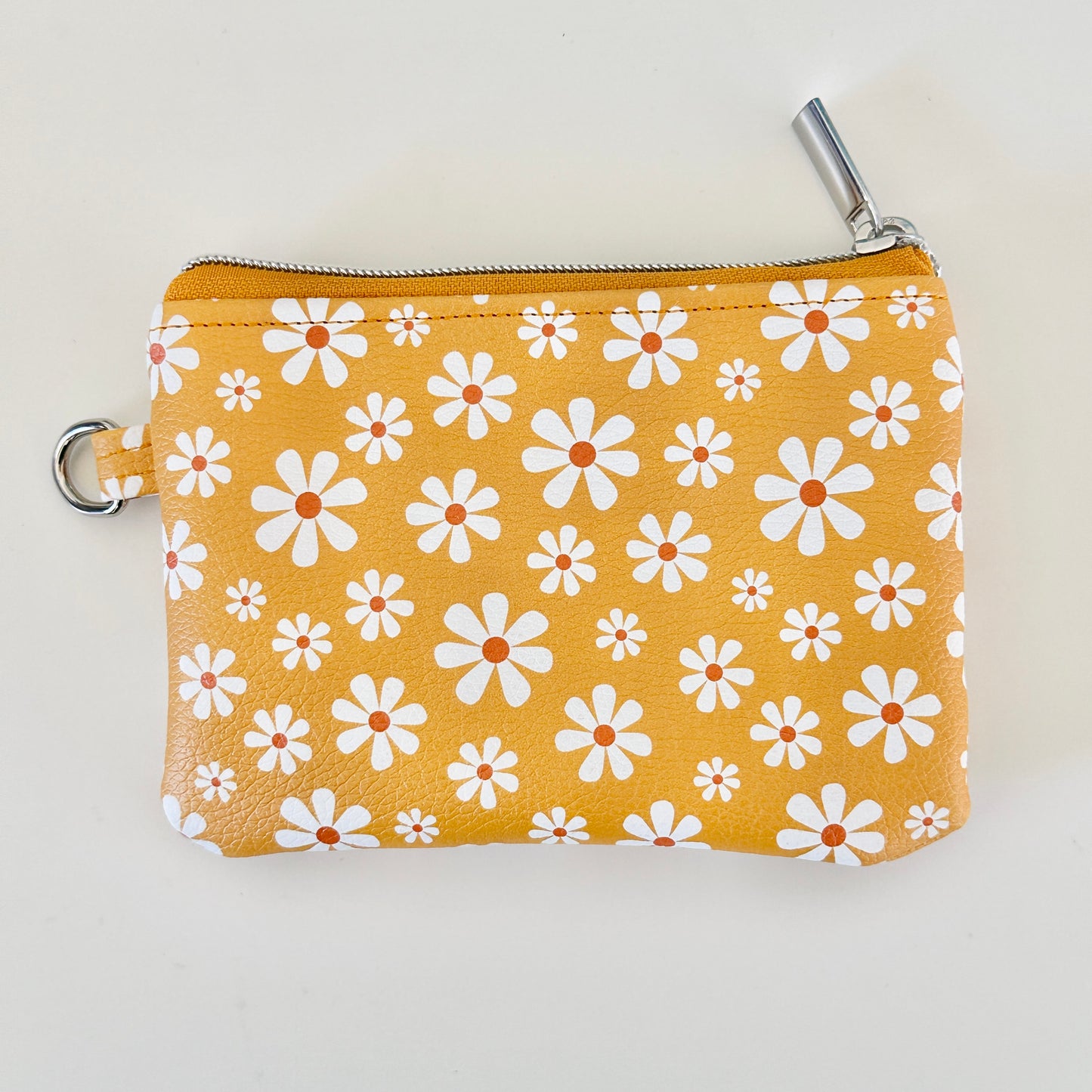 mustard Yellow coin purse with white floral pattern on a white background