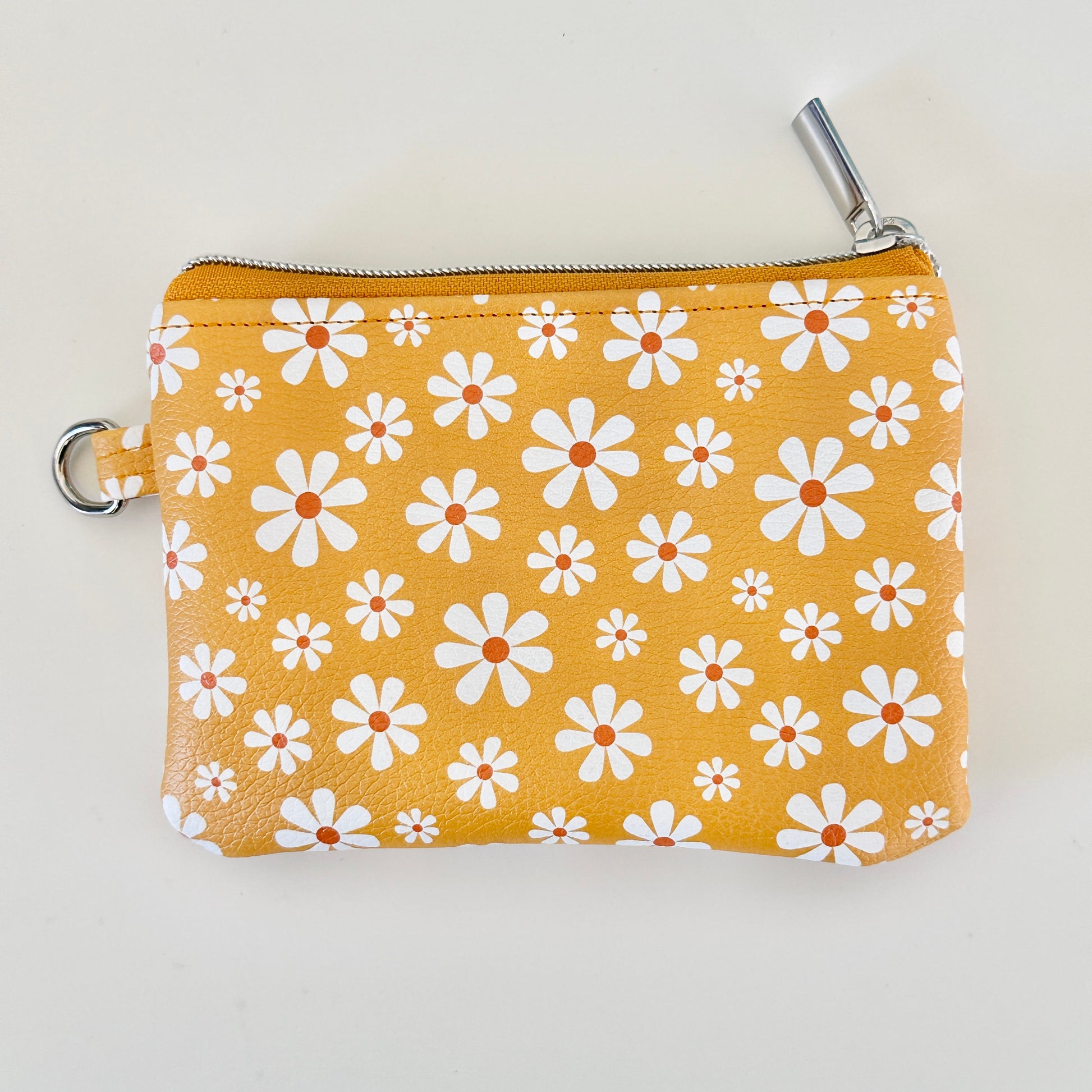 mustard Yellow coin purse with white floral pattern on a white background