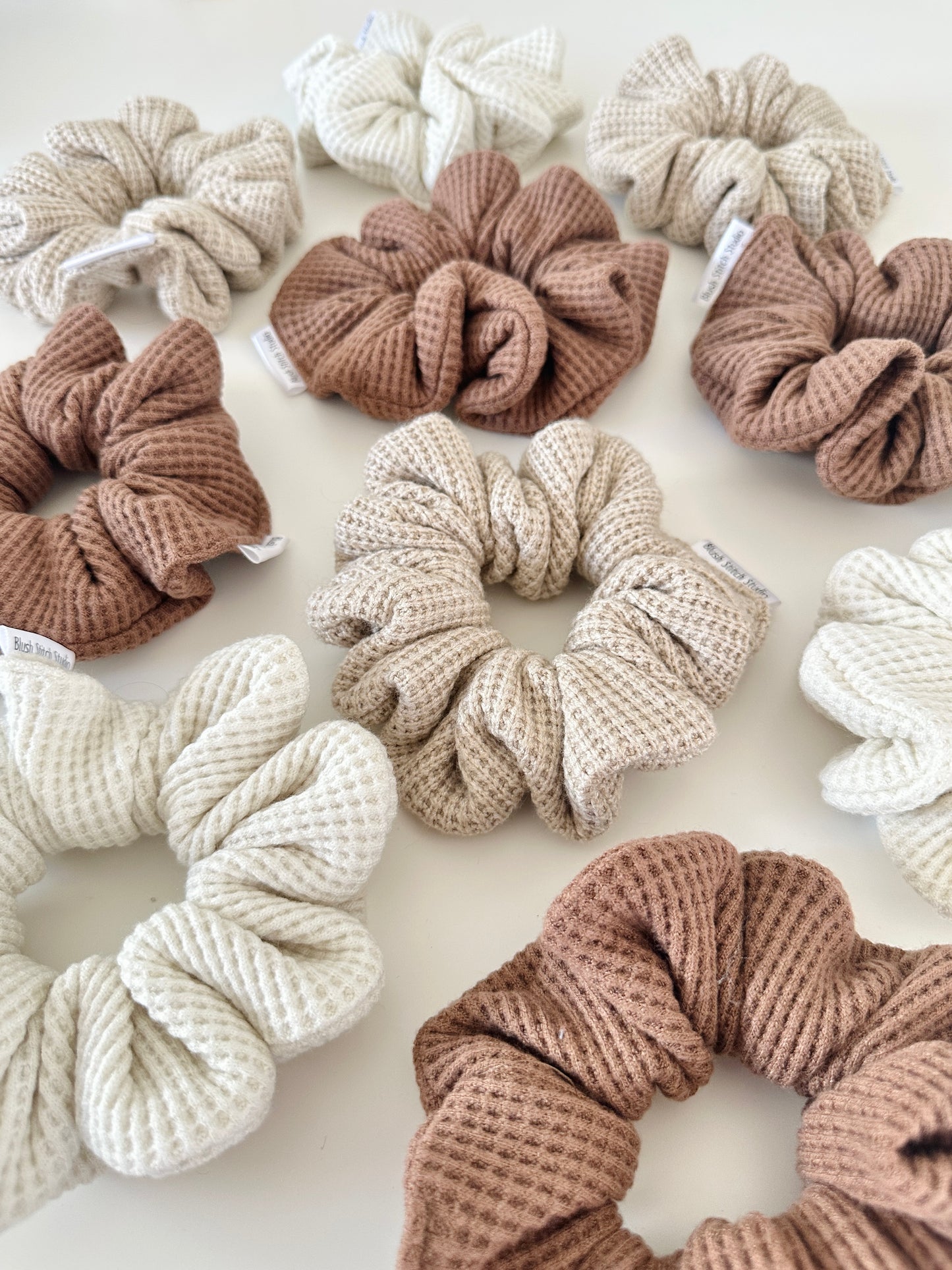Collection of textured scrunchies in various neutral colors on a light background
