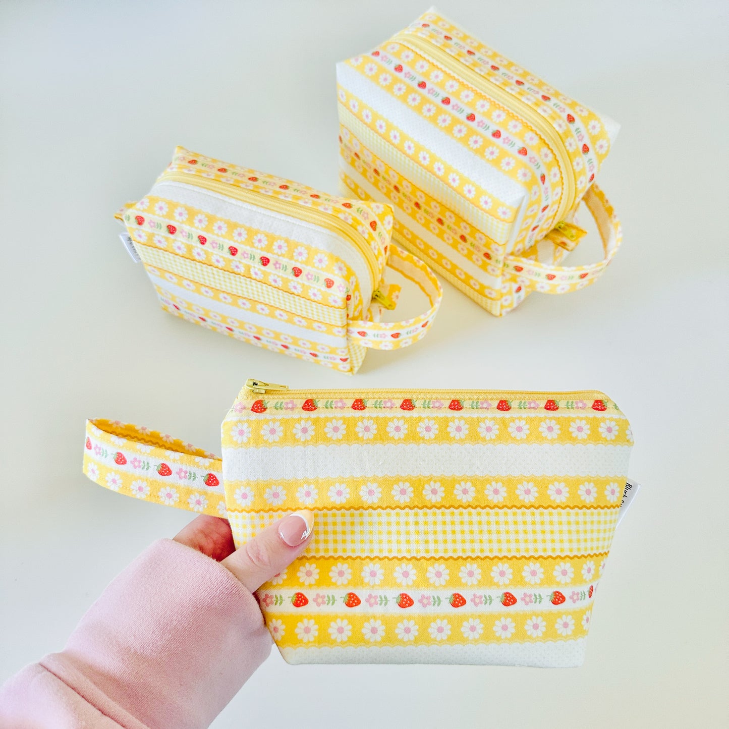 Yellow strawberry patterned makeup cosmetic bags on a white background