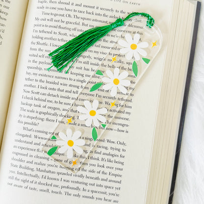 Floral daisy acrylic bookmark with green tassel on an open book