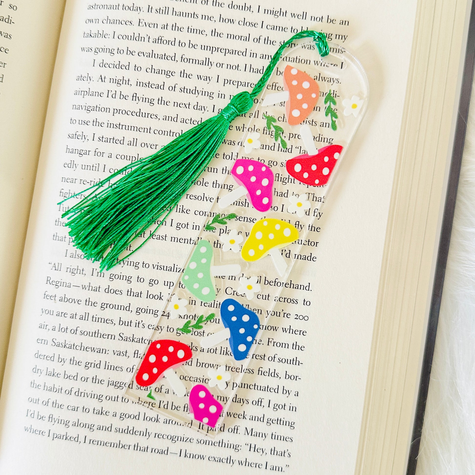 Colorful mushroom bookmark with a green tassel on an open book