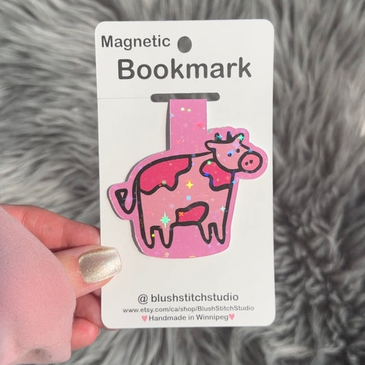 Pink cow-shaped magnetic bookmark on a Blush Stitch Studio card against a gray fur background