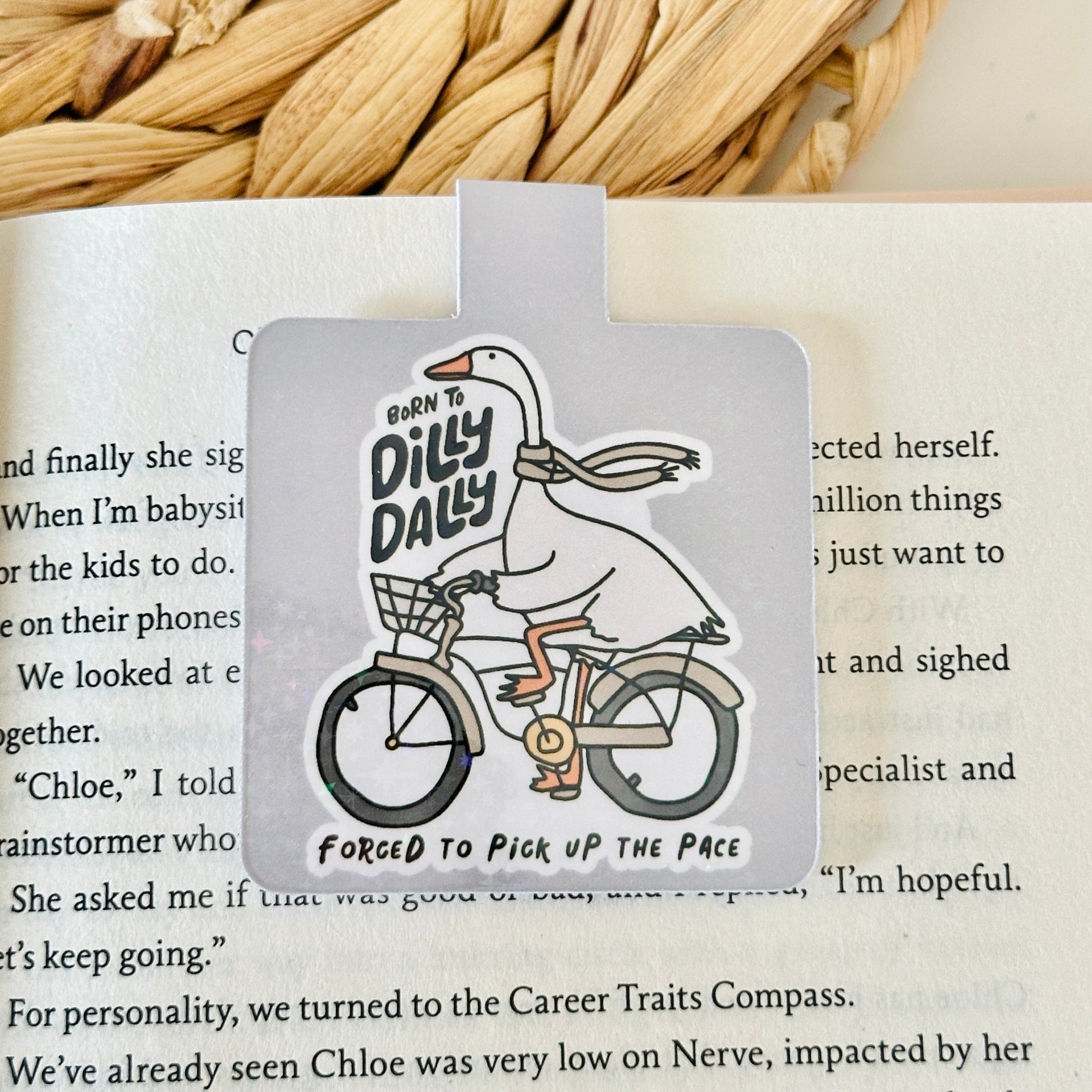 Magnetic bookmark with a cartoon goose on a bike placed on an open book