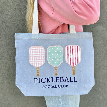 blue Tote bag with pickleball design and 'Pickleball Social Club' text held by a person.