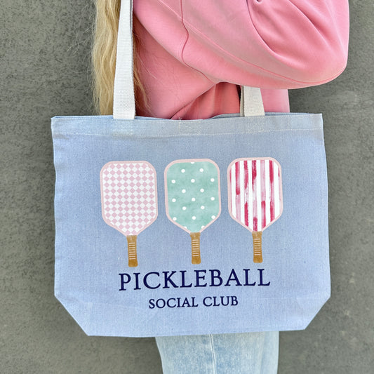 blue Tote bag with pickleball design and 'Pickleball Social Club' text held by a person.