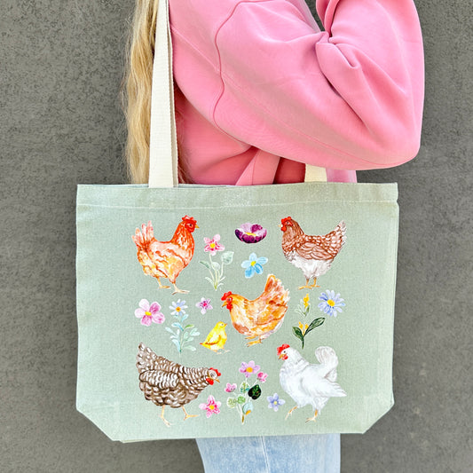 Tote bag with chicken and wildflower design held by a person in a pink jacket.