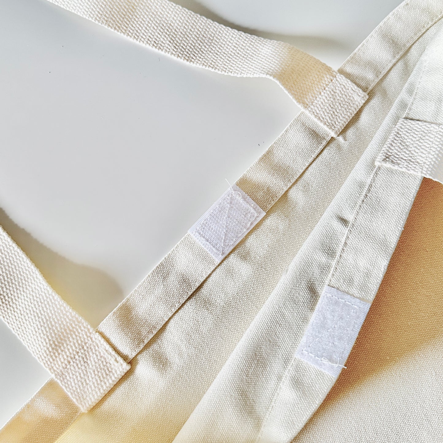 Close-up of a beige tote bag with straps and a velcro closure  on a light background