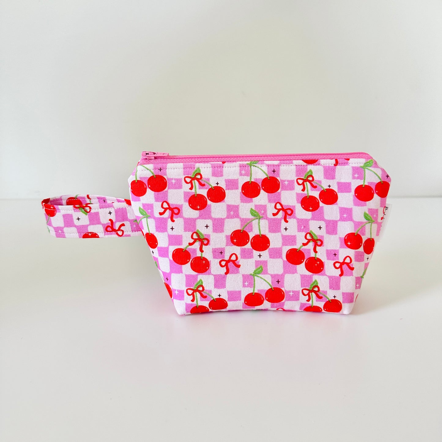 Pink pouch with cherry pattern on a white background