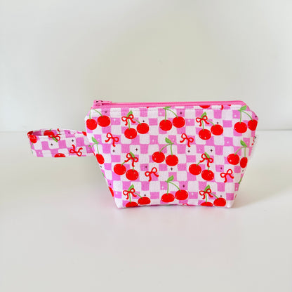 Pink pouch with cherry pattern on a white background
