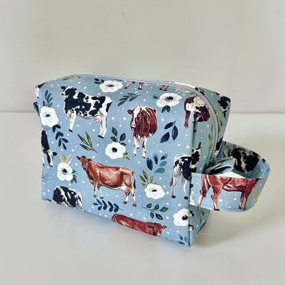 blue Fabric pouch with cow and flower pattern on a light gray background