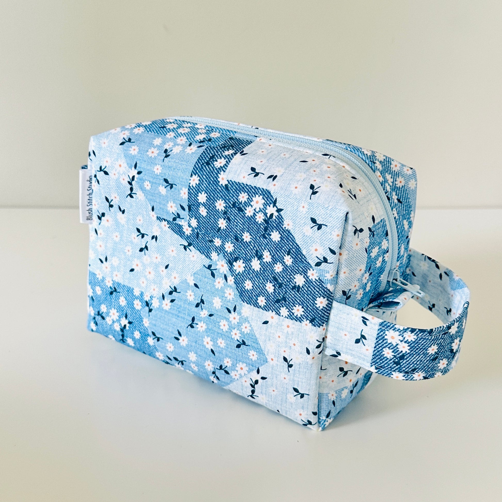 Blue floral patterned cosmetic bag on a light background