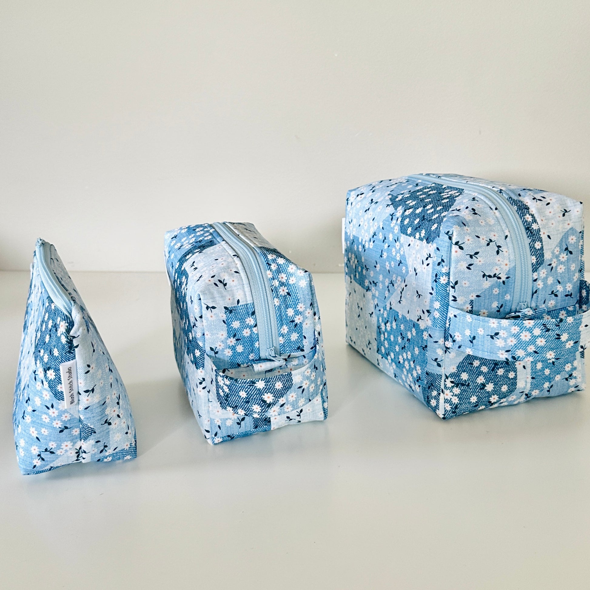 Three blue floral fabric pouches on a light background