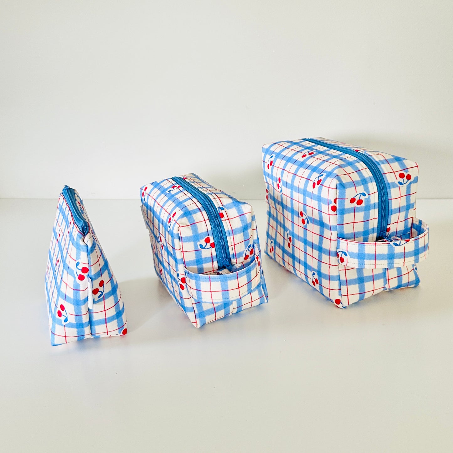 Set of three blue and white checkered bags with cherrys on a light gray background