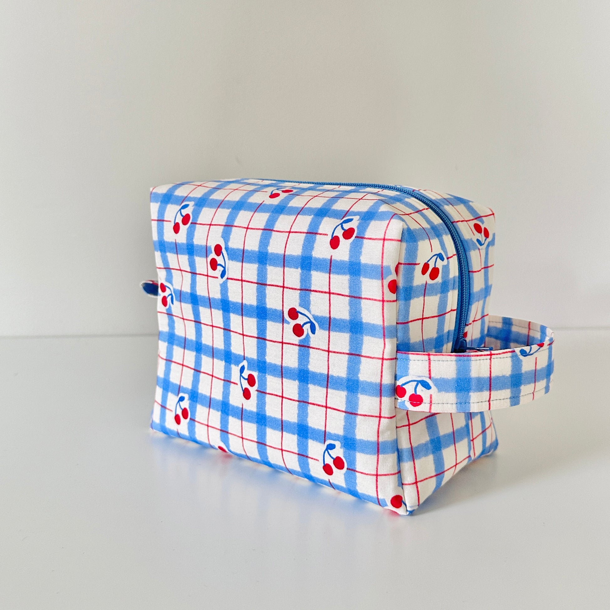 Plaid toiletry bag with cherry pattern on a white background