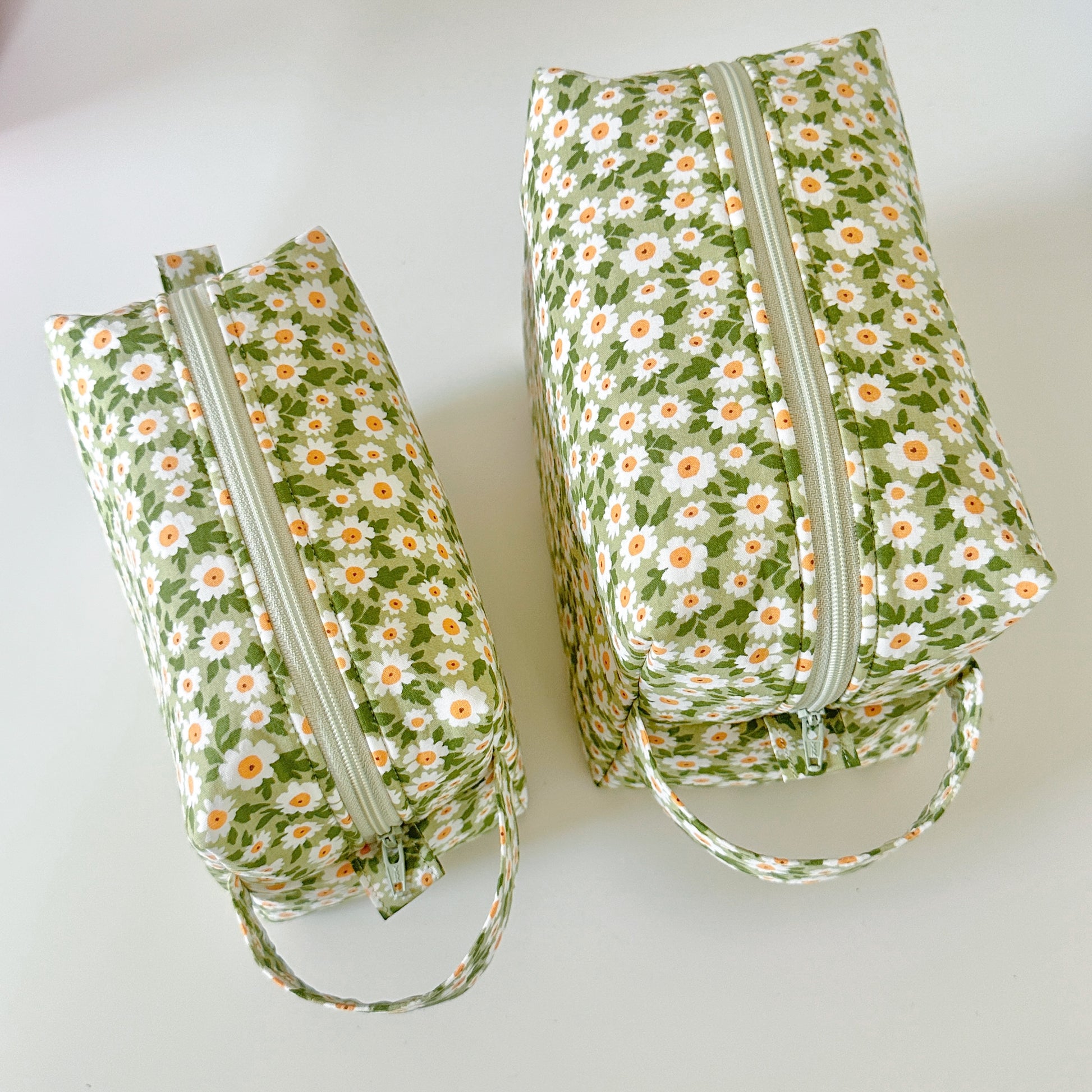 Two floral-patterned bags with zippers on a white background