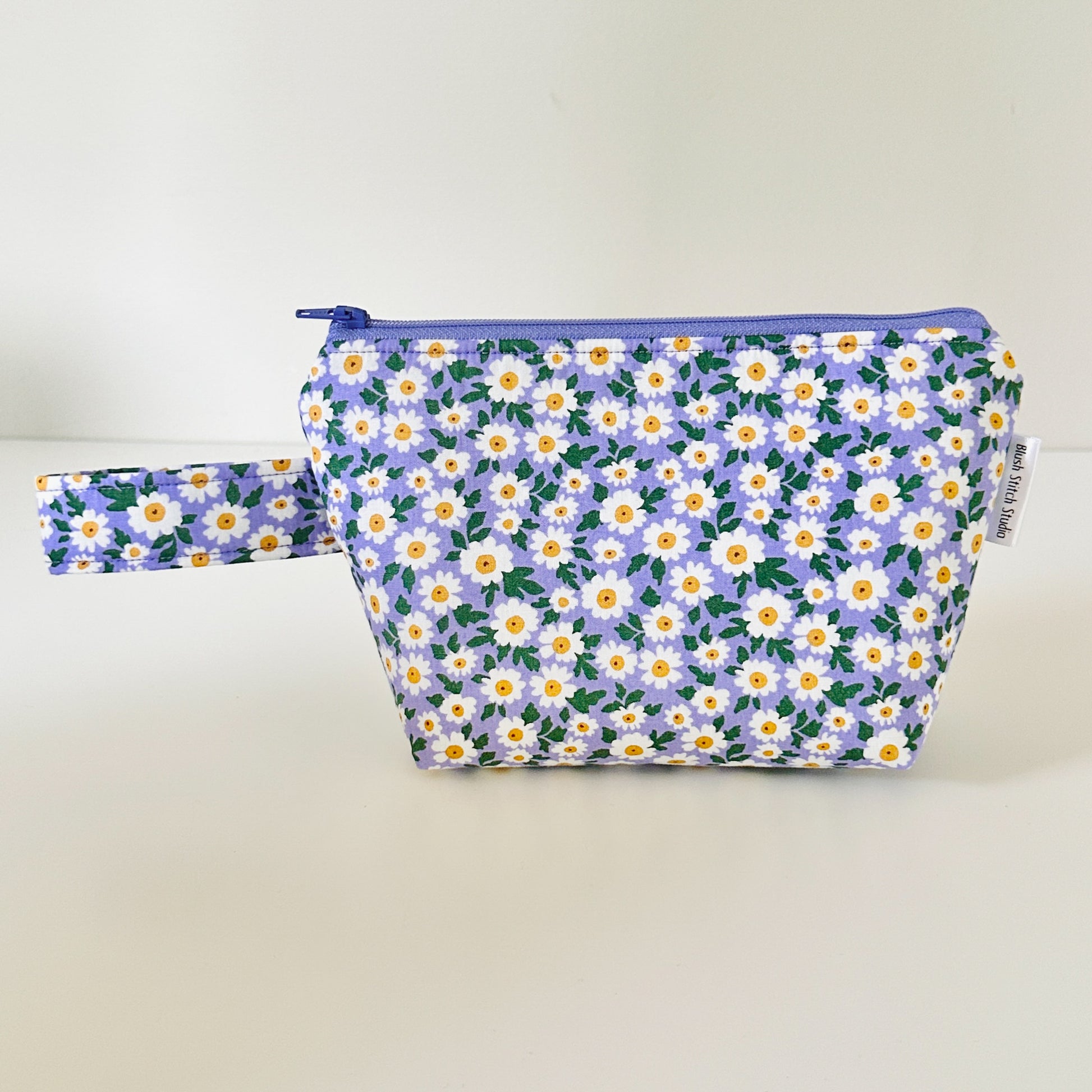 Floral-patterned pouch with a strap on a light background
