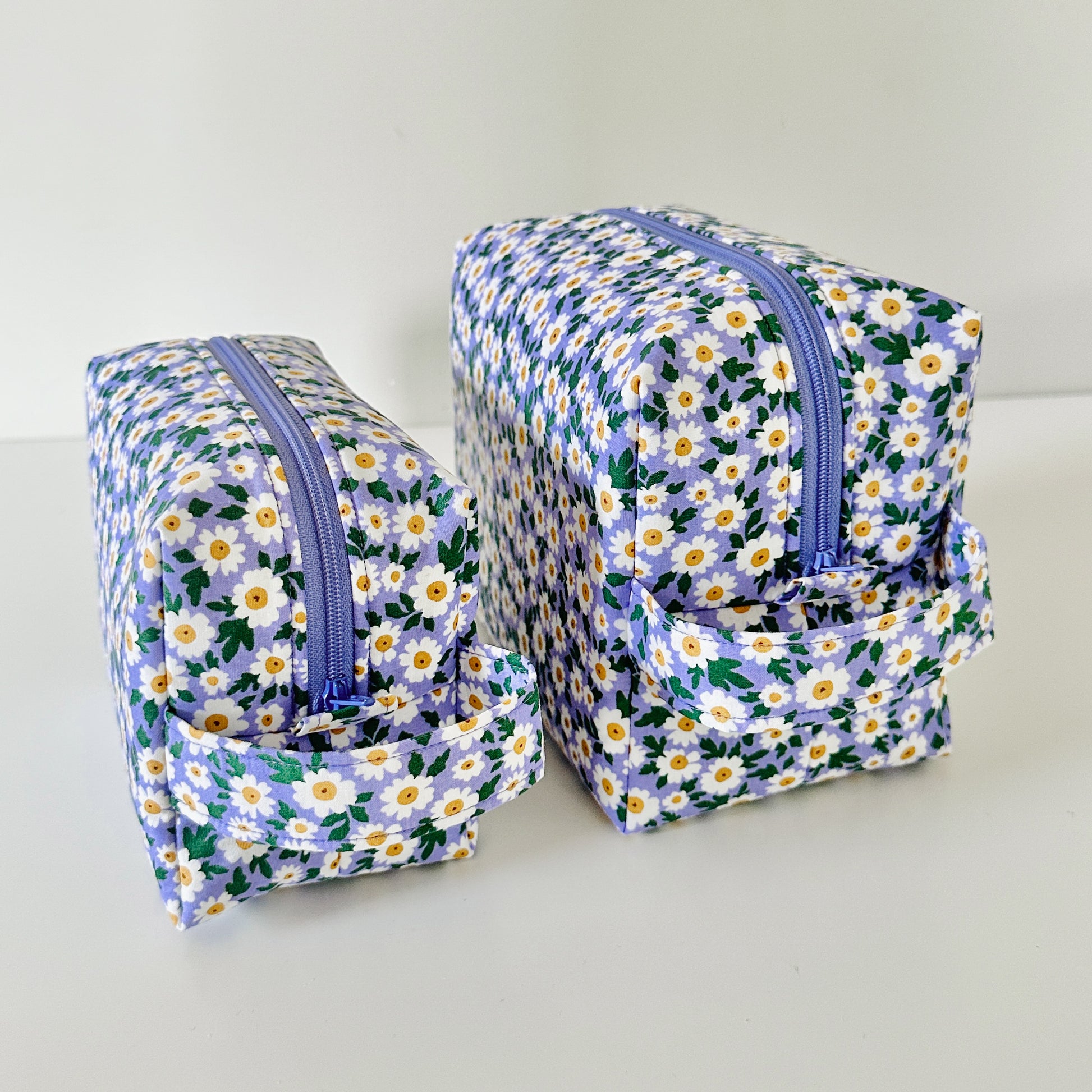 Two floral-patterned toiletry bags with zippers on a light gray background