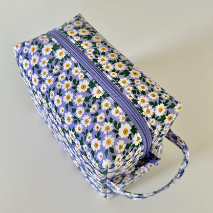 Floral-patterned rectangular bag with a purple zipper on a light gray background