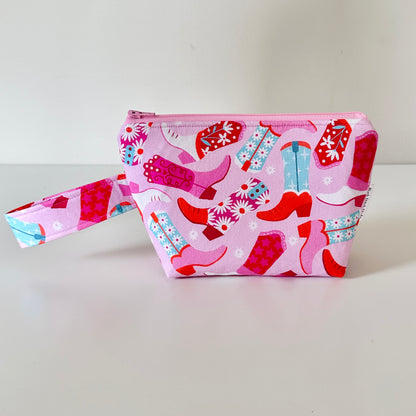 Pink makeup bag with cowboy boot pattern on a white background